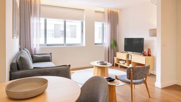 Een moderne woonkamer met een bank, een eettafel, een televisie en een bijzettafeltje.