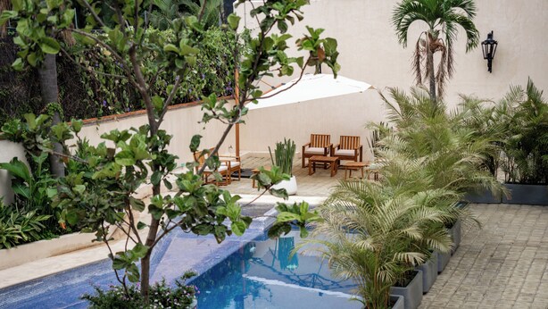 Un espace piscine aménagé avec des sièges, des plantes en pot et un luminaire fixé au mur.