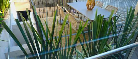 Un patio al aire libre con mesa y sillas, rodeado de plantas.