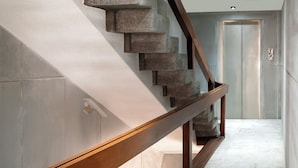 Un escalier moderne avec une rampe en bois et des marches en pierre menant à une porte.