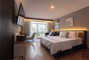 Una habitación de hotel moderna con cama, escritorio, silla y televisor.