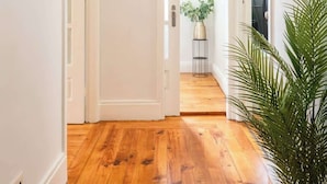 A hallway with wooden flooring, white walls, and a potted plant. - Modern & Cozy Flat with Workspace by HostWise (Porto)