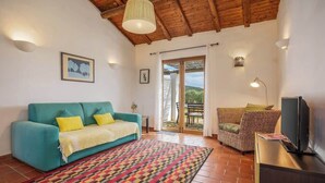 Una sala de estar acogedora con un sofá color turquesa, una alfombra estampada y un televisor sobre un mueble.