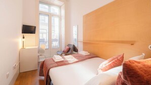 A hotel room with a bed, a desk, a chair, a TV, and a window. - Porto Lounge Hostel - Cozy Bright Room w Balcony (Porto)