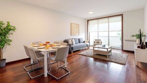 Una sala de estar moderna con una mesa de comedor, sillas, un sofá, una mesa de centro y un ventanal grande.