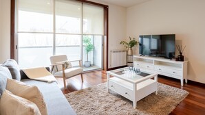 Una sala de estar moderna con un sofá, una mesa de centro, un televisor y una planta.