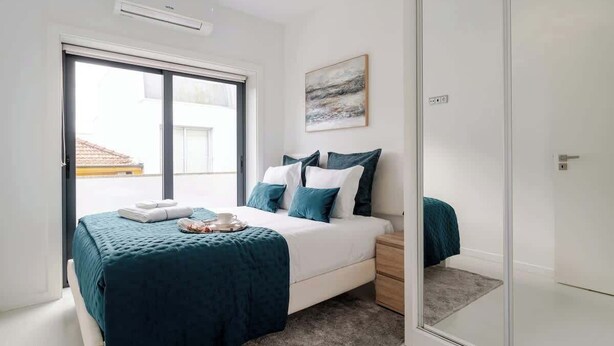 A bedroom with a bed, a nightstand, a window, and a painting on the wall. - Sleek Apartment with Balcony by HostWise (Porto)