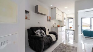 A modern living room with a black sofa, a grey rug, and a dining area with a table and chairs. - Sleek Apartment with Balcony by HostWise (Porto)
