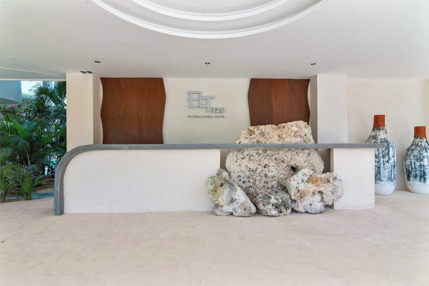 A reception desk with a stone centerpiece, wooden panels, and two decorative vases.