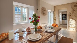 A breakfast setting with a table set for two, including croissants, milk, and a vase with flowers.
