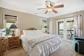 A bedroom with a bed, bedside tables, a ceiling fan, and a balcony with curtains. - Coweeta Rapids: Your Elevated Creekside Escape (Otto)