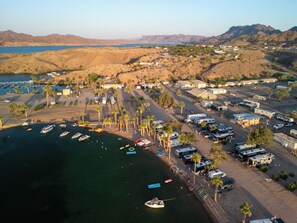 Vista aérea de una zona costera con vehículos recreativos, barcos y un puerto deportivo.