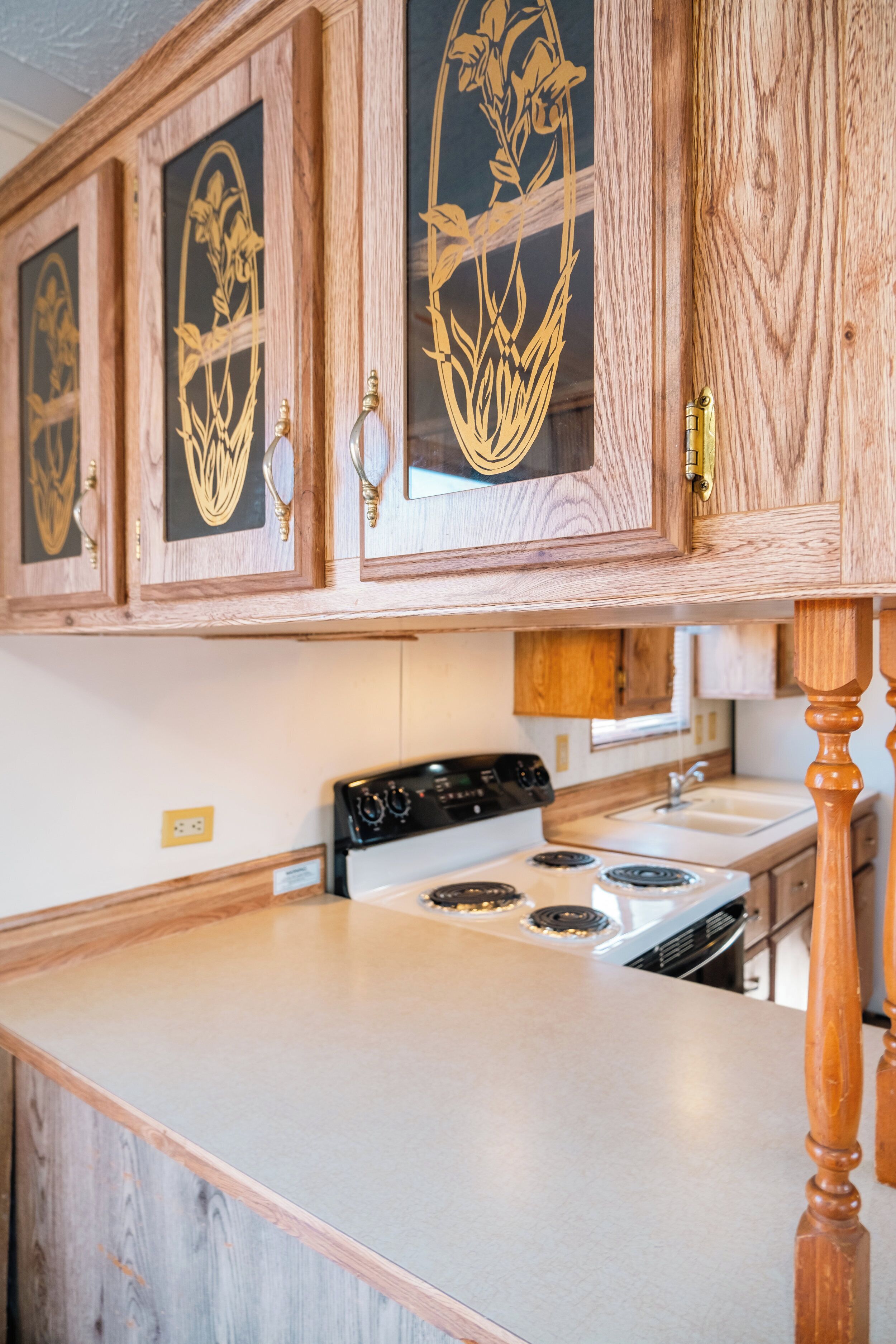 Cocina con armarios de madera, estufa y lavamanos.