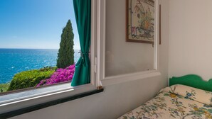 A bedroom with a view of the sea, a green curtain, and a floral bedspread. - Sibilla D'Oltremare - Sestri Levante (Sestri Levante)