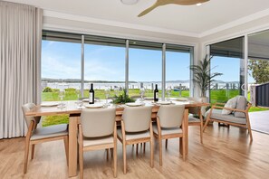 A dining area with a large window overlooking a marina and greenery. - Tilligerry Beach Retreat (Taylors Beach)