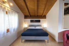 Ein Schlafzimmer mit einem Bett, Holzbalkendecke, einer Wanduhr und Nachttischlampen.