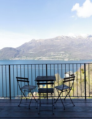 Un balcon avec deux chaises et une table, d’où l’on a vue sur un lac et des montagnes.