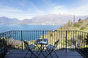 Ein Balkon mit Tisch und Stühlen mit Blick auf einen See und Berge.
