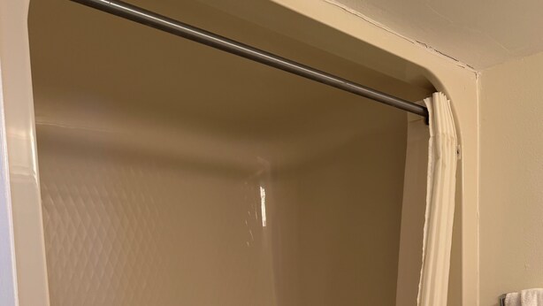 A bathroom with a shower enclosure, a toilet, and a towel rack. - South Shores Motel (Daytona Beach Shores)