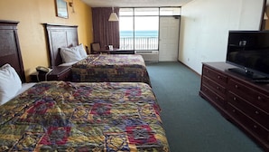 Una camera d'albergo con due letti, televisione, una cassettiera, una scrivania e vista sull'oceano.