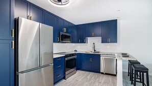 Uma cozinha moderna com armários azuis, eletrodomésticos de aço inoxidável e bancada branca.