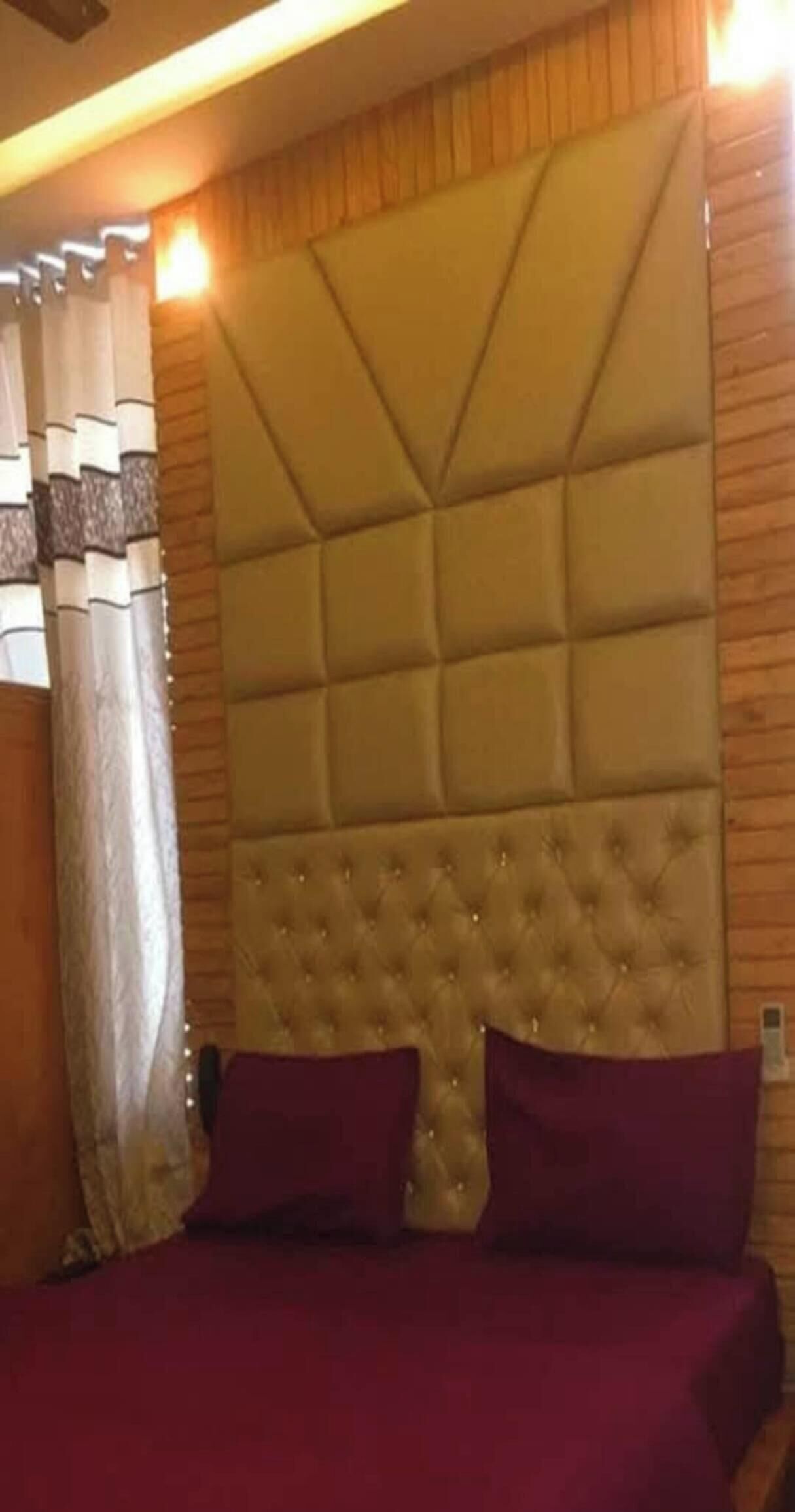 A bedroom with a tufted headboard, a bed with red bedding, and wooden paneling on the walls.