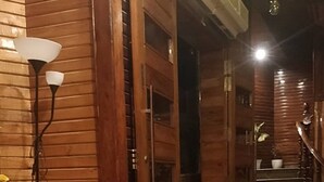A wooden hallway with a tiled floor, a staircase, and a wall-mounted light fixture. - The Silver Oak Banquet and Motel  (Balachaur)