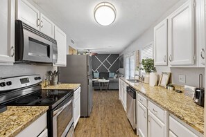 A modern kitchen with granite countertops, stainless steel appliances, and white cabinetry. - 30% OFF Family Getaway-4 beds! AIR Hockey & Arcade (Plano)