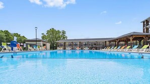 Una piscina con sillones de descanso y una zona de estar cubierta.