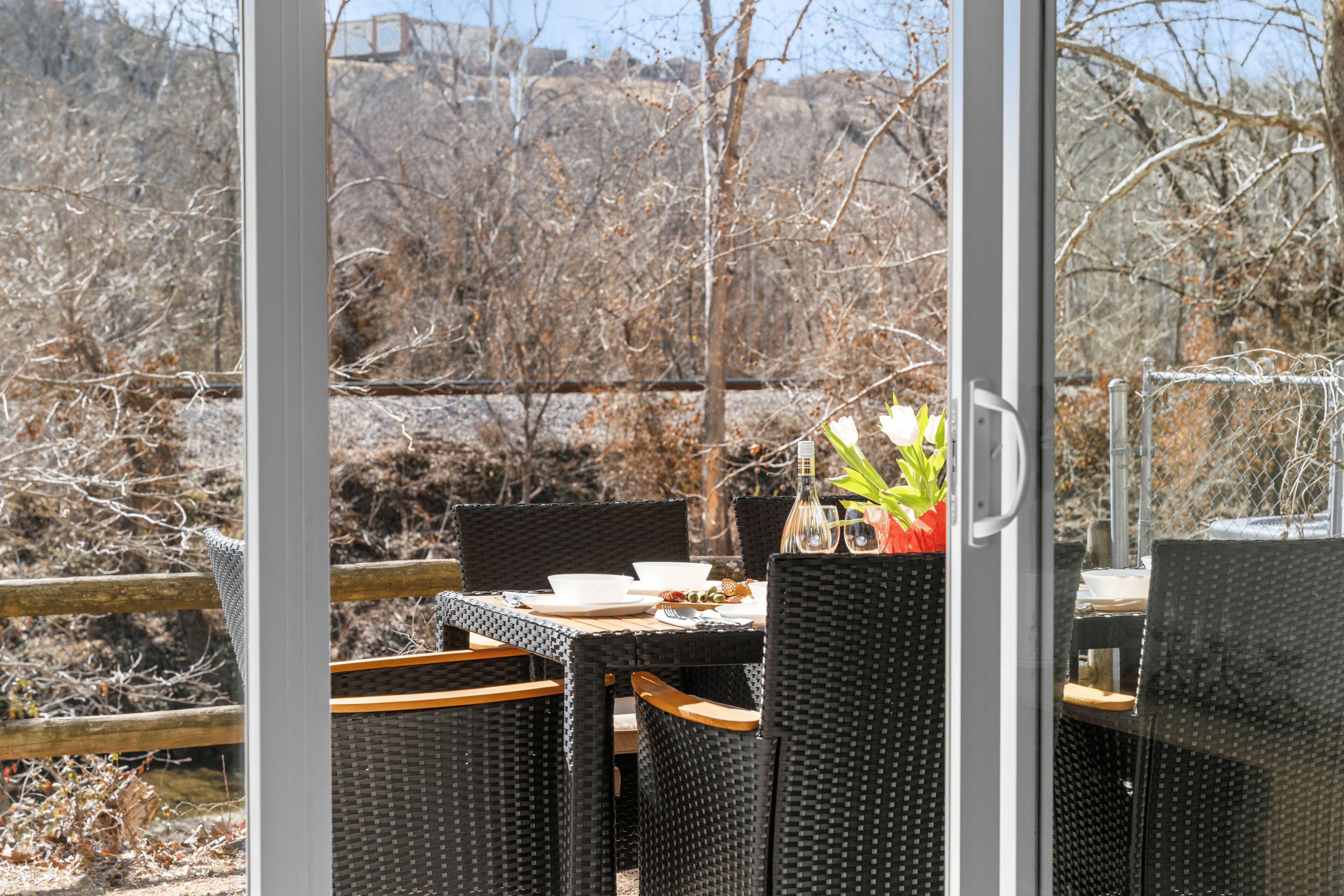 Un espace extérieur aménagé pour les repas, avec des chaises en osier et une table pour deux, offrant une vue sur un paysage naturel.