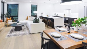 A modern apartment with a living area, dining space, and kitchen. - Peak To Green Getaway - Townhouse (Revelstoke)