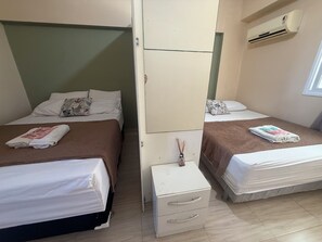 A hotel room with two beds, a wardrobe, a small table, and an air conditioning unit. - BP03 - Varanda Ventilada No Estilo Bali Lounge (Caucaia)