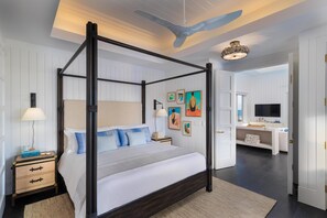 A four-poster bed with a dark frame, a bedside table with drawers, a lamp, and a rug.