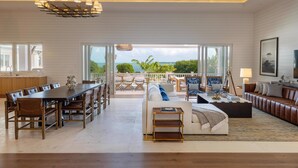 A spacious living area with a dining table, sofas, and a view of the outdoors.
