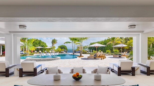 A modern outdoor seating area with a pool, lounge chairs, and umbrellas.