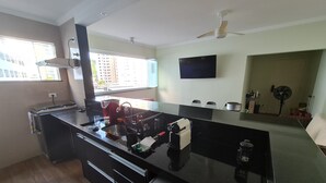 A modern kitchen with a large island, built-in appliances, and a window with a view of buildings. - Beachfront accommodation on Astúrias Beach. Spacious and comfortable. WiFi. (Guarujá)