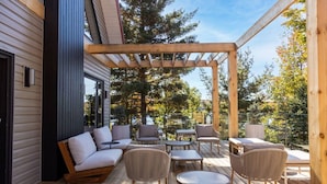 A wooden deck with outdoor furniture, including a sofa and chairs, under a pergola. - Nourish + Reset at Dimensions | Cabin Ten | Breakfast Included (The Blue Mountains)