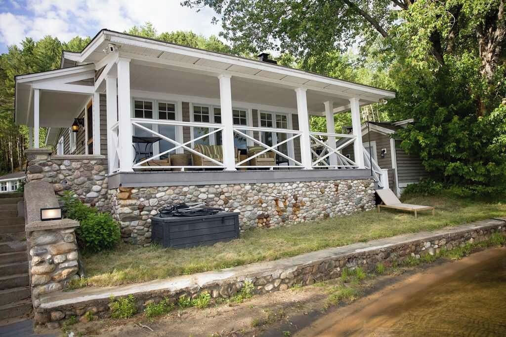 A house with a covered porch, stone foundation, and a small outdoor seating area.