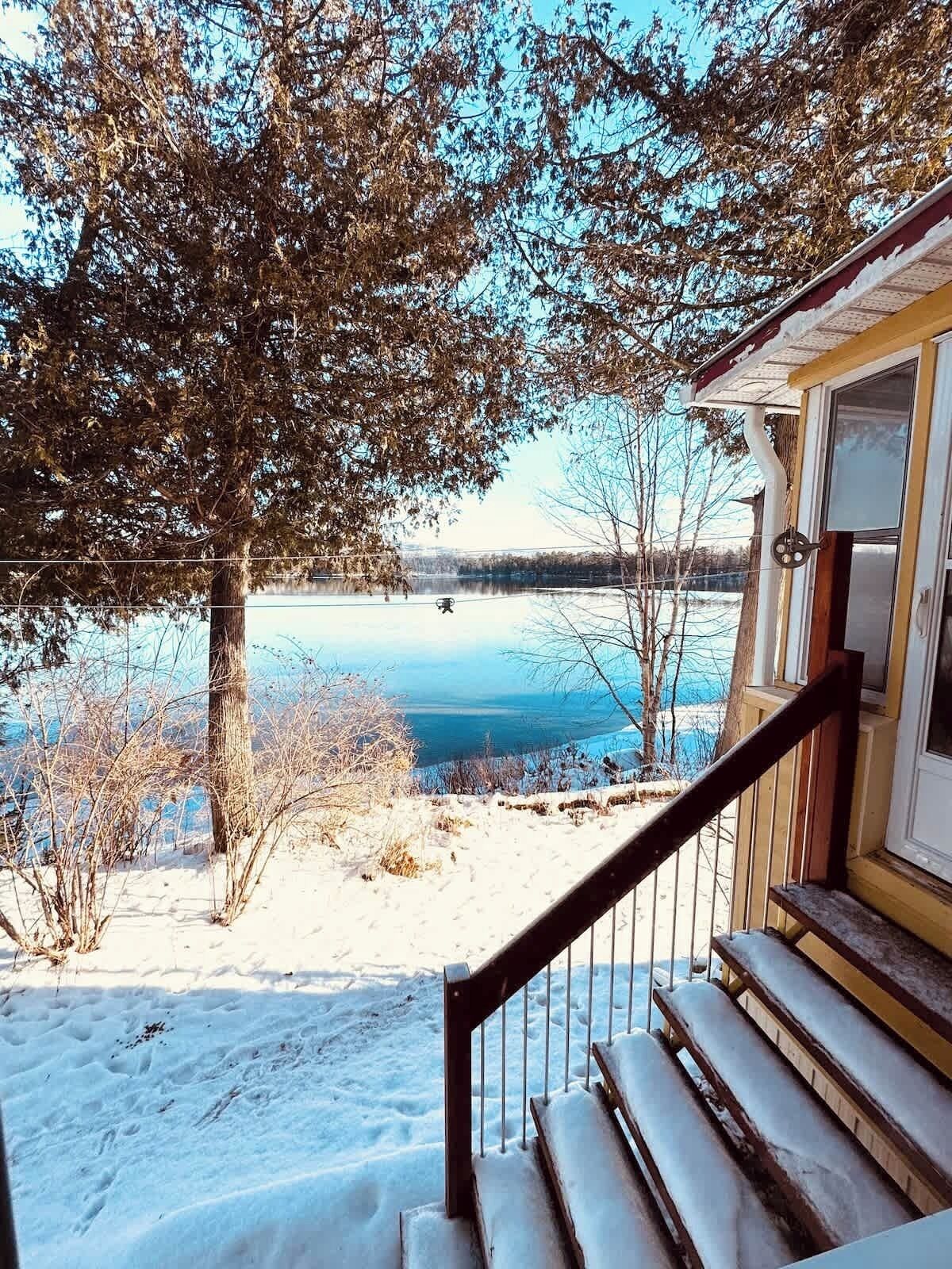 A wooden staircase leading to a house with a view of a lake and trees.