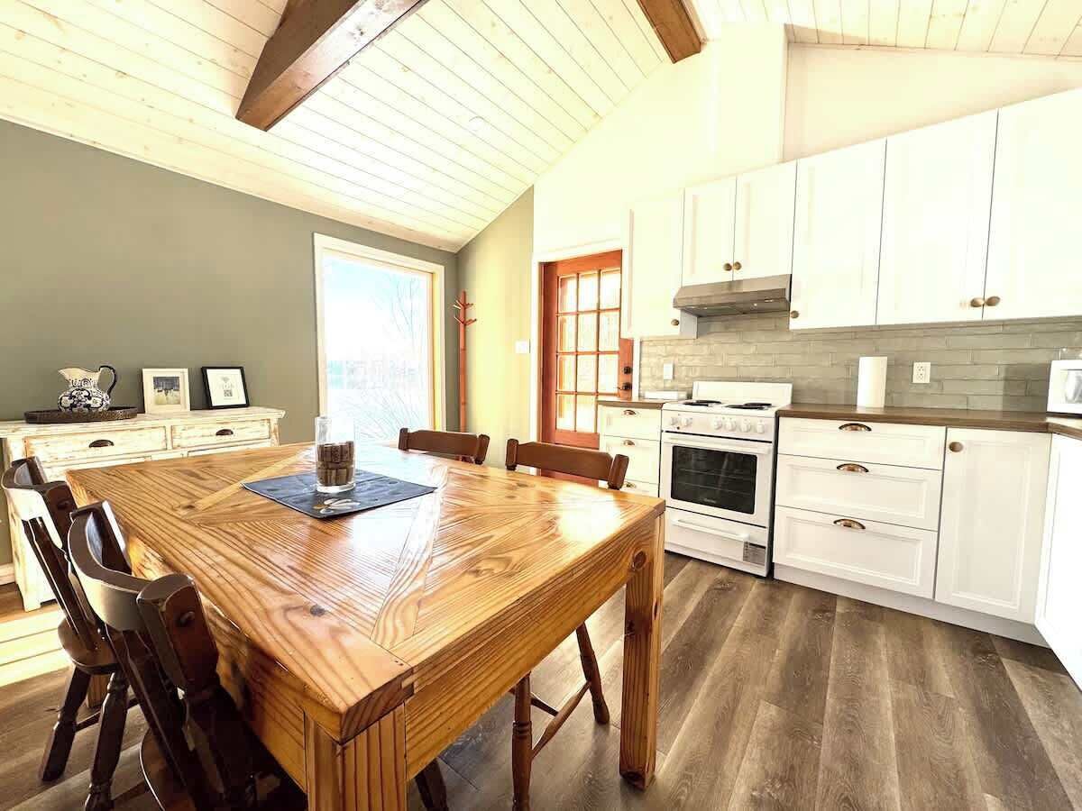 A kitchen with white cabinets, a wooden dining table, and a window.