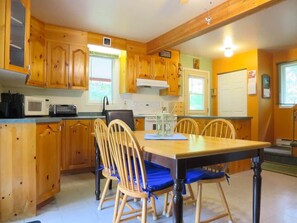 A kitchen with wooden cabinets, a dining table with chairs, and a microwave.