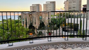 Un balcón con vistas a edificios de la ciudad, barandilla y un jardín con piedras y plantas.
