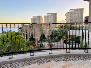 Un balcon donnant sur les bâtiments de la ville, avec une balustrade et un jardin agrémenté de galets et de plantes.