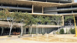 Un edificio de varios pisos con diseño moderno, que presenta un patio central con fuente de agua y abundante vegetación.