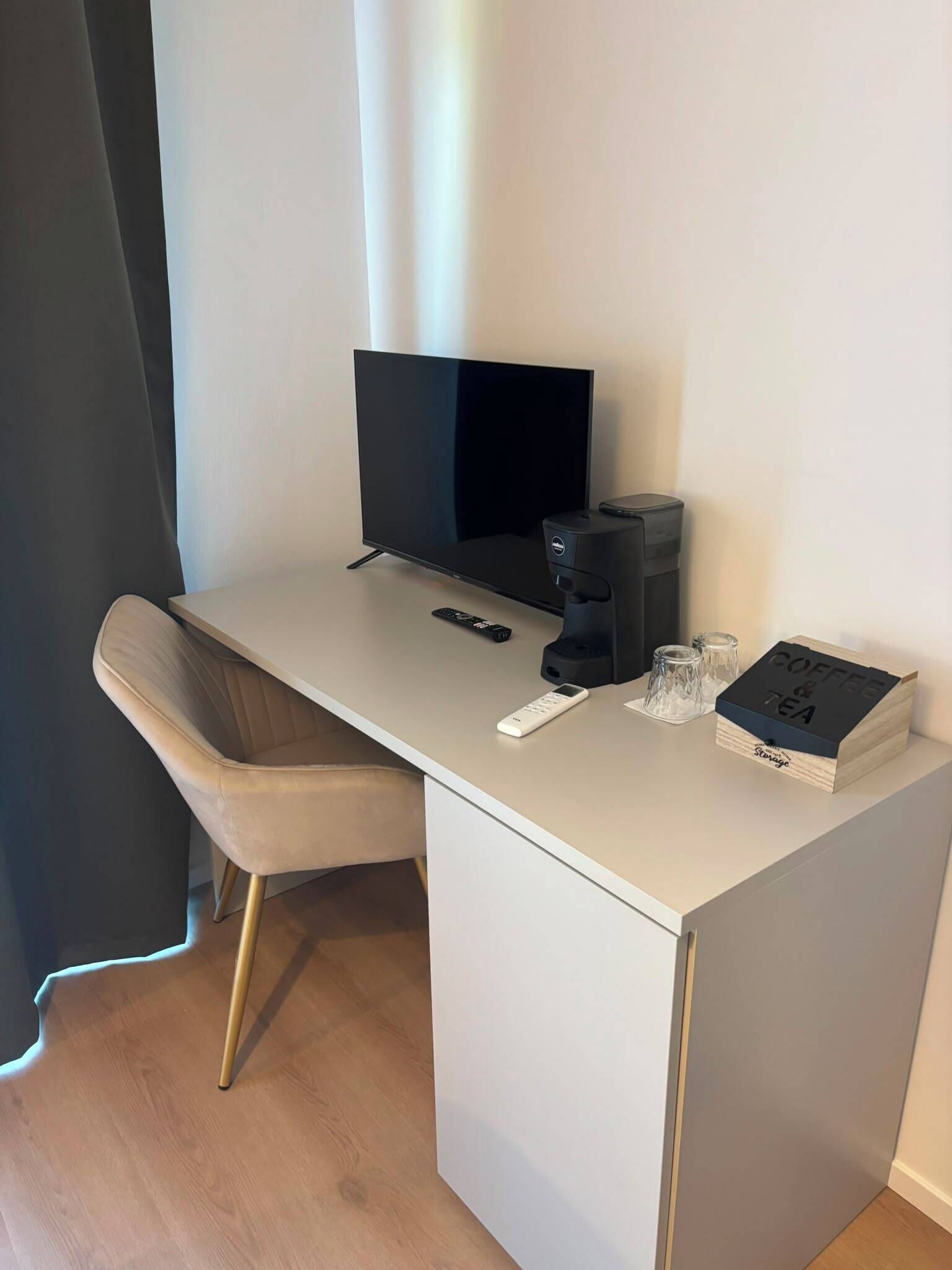 A modern office desk with a flat-screen monitor, a coffee machine, and a box labeled 'COFFEE & TEA'.