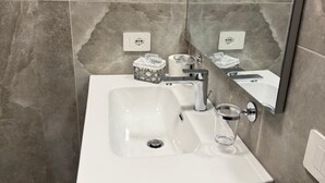 A bathroom with a white sink, a glass, and a towel dispenser. - Urban Stay Siena (Siena)