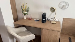 A wooden desk with a white chair, a coffee maker, a lamp, and a vase with yellow flowers. - Urban Stay Siena (Siena)