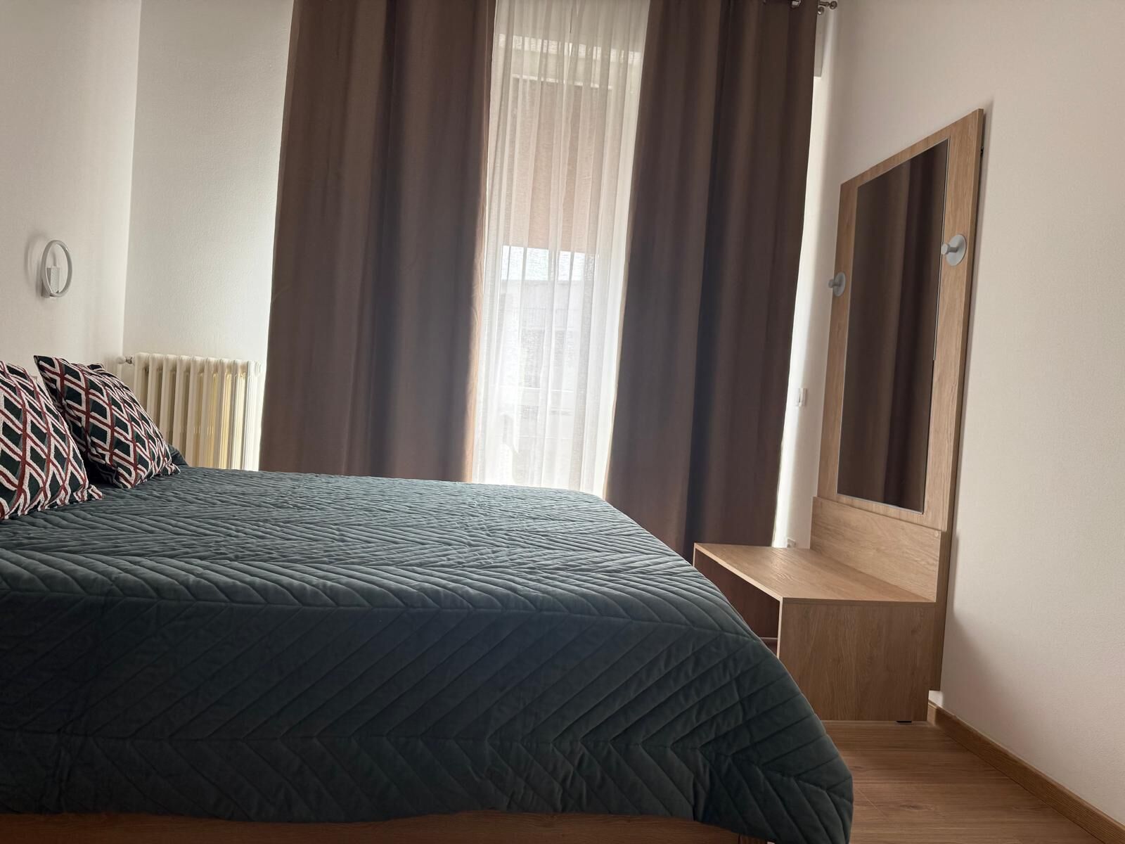 Un dormitorio con una cama grande, un banco de madera, un espejo y cortinas de encaje.