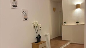 A room with a chair, a radiator, a small table with a plant, and artwork on the wall. - Urban Stay Siena (Siena)