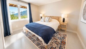 Une chambre à coucher avec un lit, des lampes de chevet, un tapis à motifs et une fenêtre avec des rideaux.